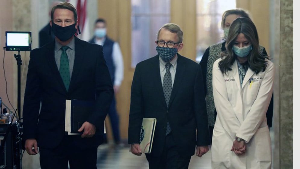 Wearing their protective masks, from left, Ohio Lt. Gov. Jon Husted, Gov. Mike DeWine, and Ohio Department of Health Director Dr. Amy Acton walk into a coronavirus news conference at the Ohio Statehouse.
