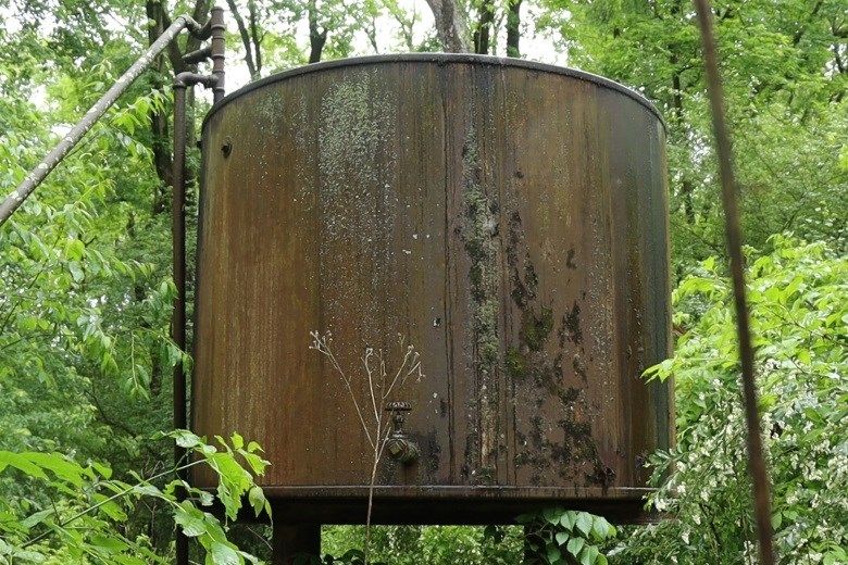 A large, rusting tank that is part of an orphaned oil well near the Shenango River Lake