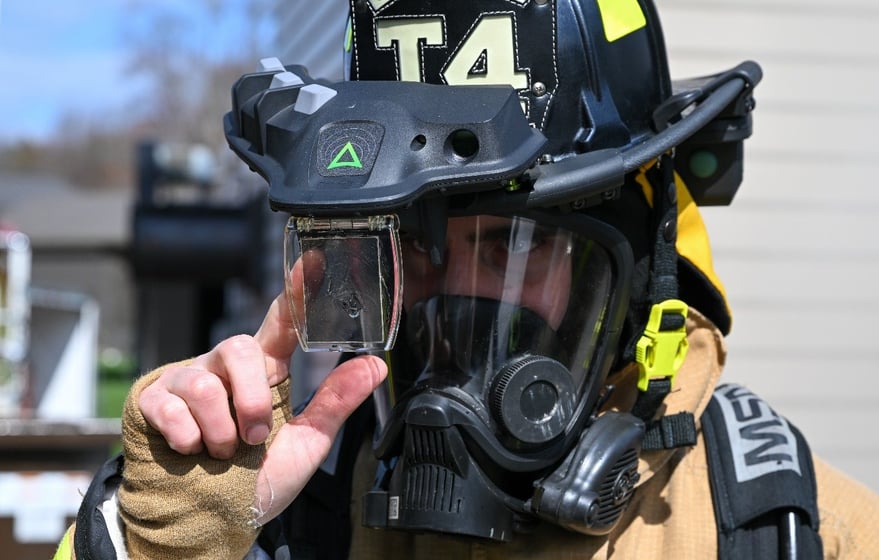 A firefighter equipped with an augmented reality helmet attachment system preps a hose before responding to a live-fire training event at YARS,